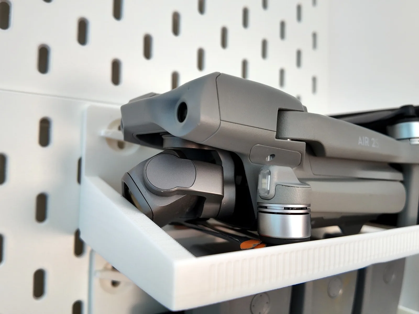Photo: a folded DJI Air 2S lying on the printed SKADIS sled on a pegboard