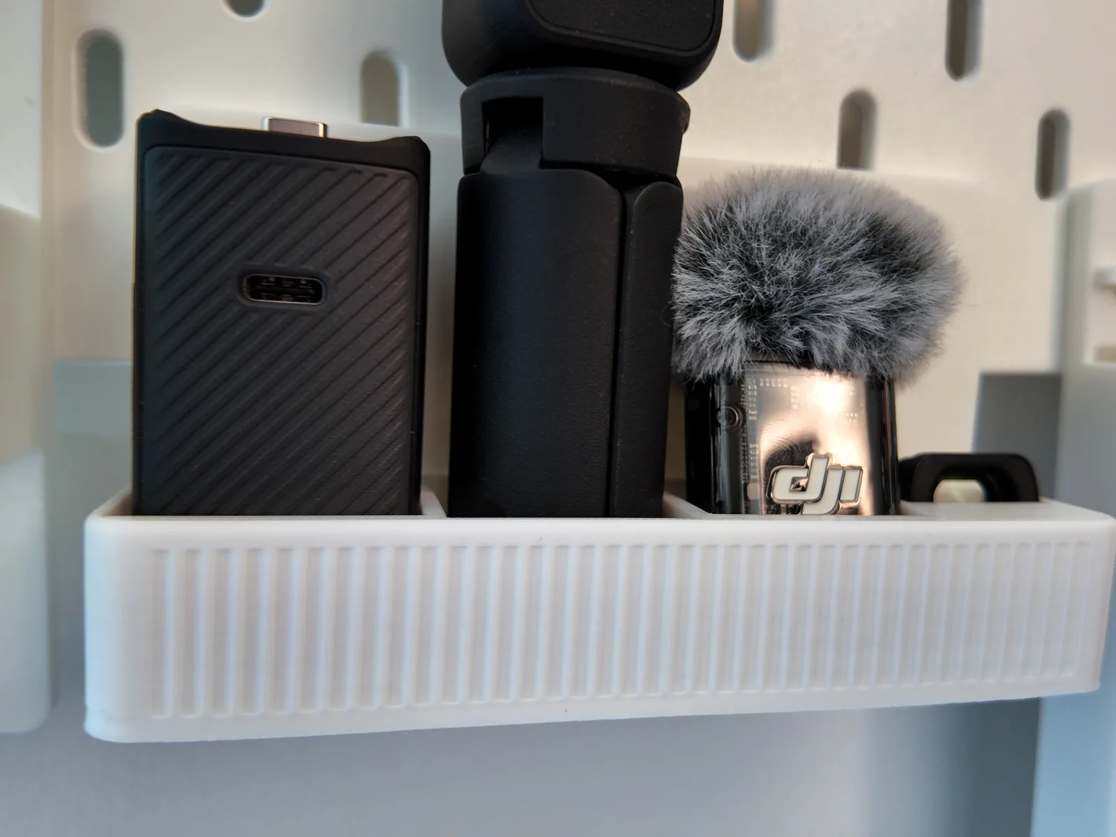 Photo: the printed shelf holding the Pocket 3 battery handle, mini tripod and mic transmitter